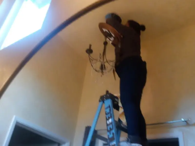Electrician installing a chandelier in a Whitney residence